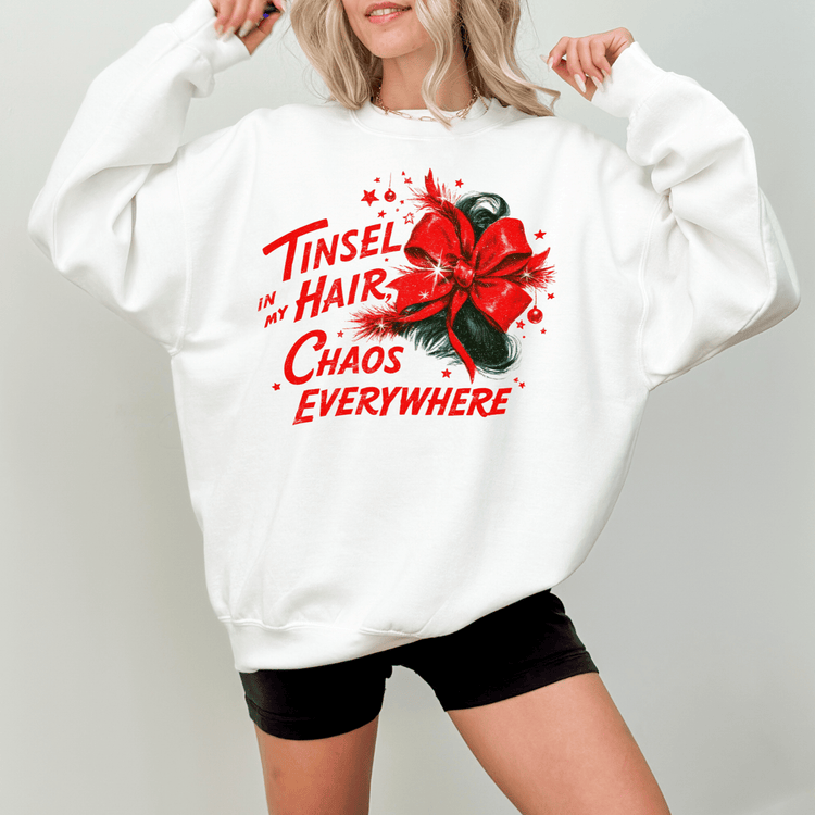 A woman wearing a white sweatshirt with a red bow and text printed on it.