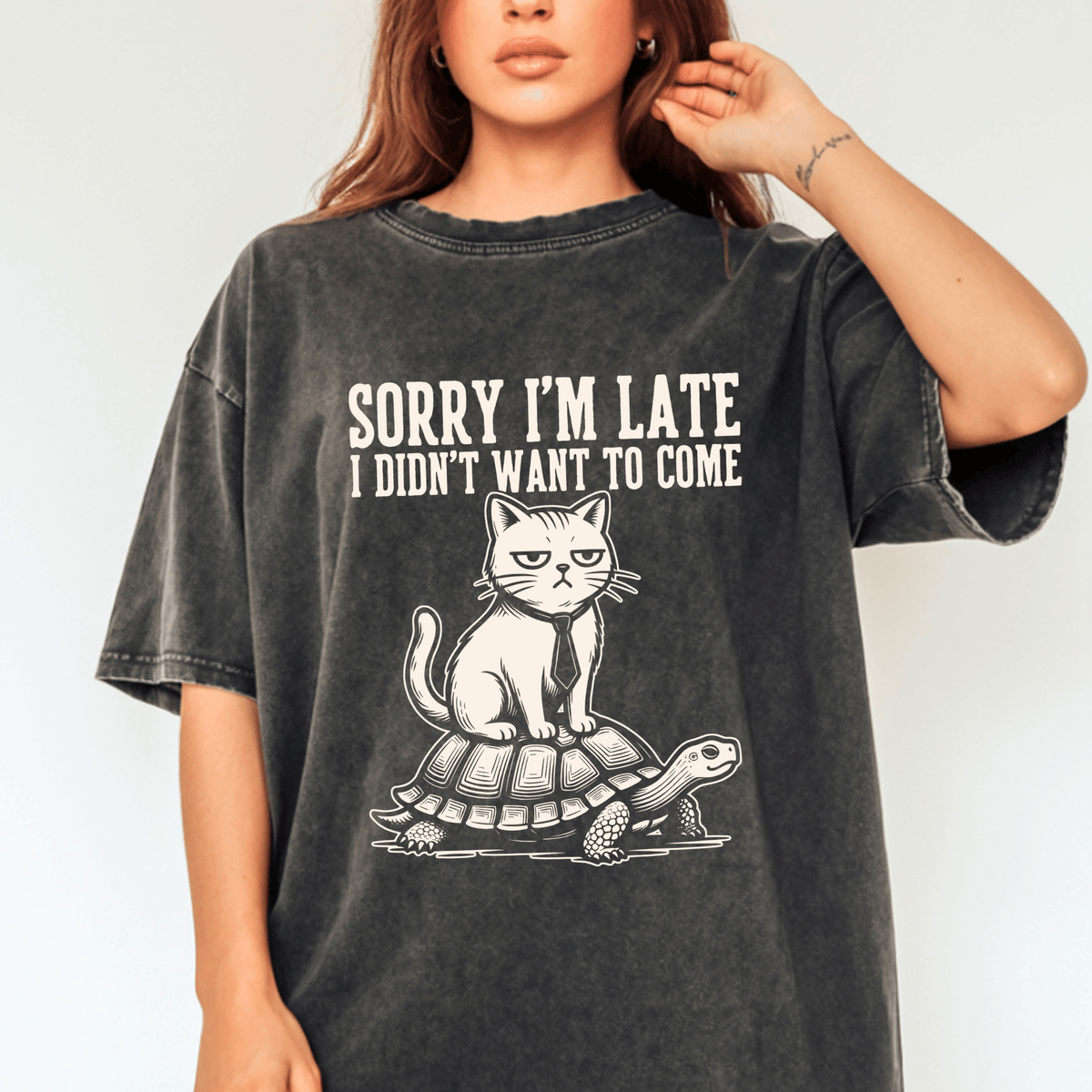 A woman wearing a black t-shirt with a graphic design of a cat sitting on a turtle.