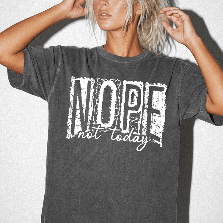 A woman wearing a gray t-shirt with the text "NOPE not today" printed on it.