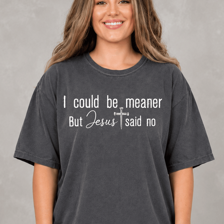 A woman wearing a gray t-shirt with the text "I could be. meaner But Jesus said no" printed on it.