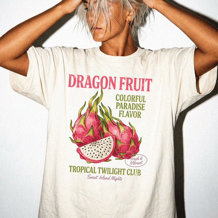A person wearing a white t-shirt with a graphic design of dragon fruit and text promoting a tropical fruit club.
