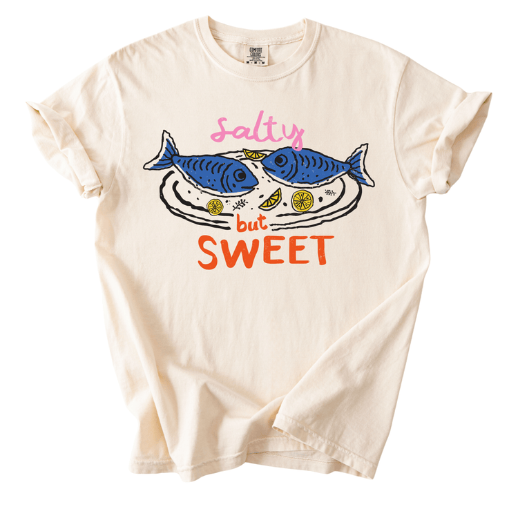 A white t-shirt with a graphic design featuring two fish and the text "salty but sweet" printed on it.