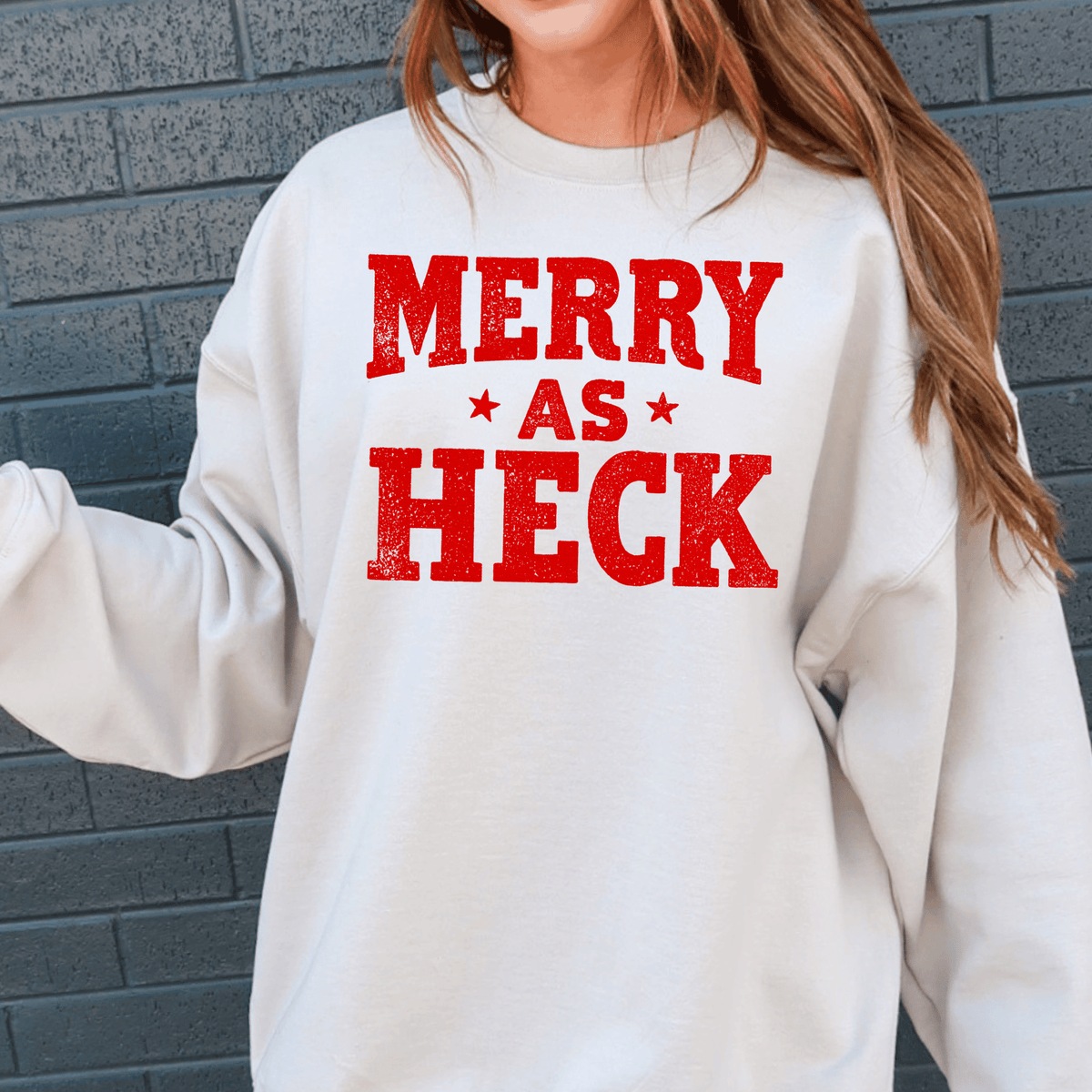 A person wearing a white sweatshirt with the text "MERRY AS HECK" printed on it.
