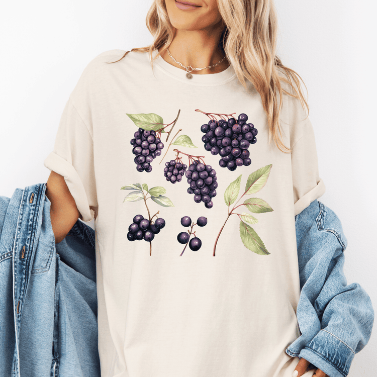A woman wearing a white t-shirt with a graphic design of purple grapes and green leaves.