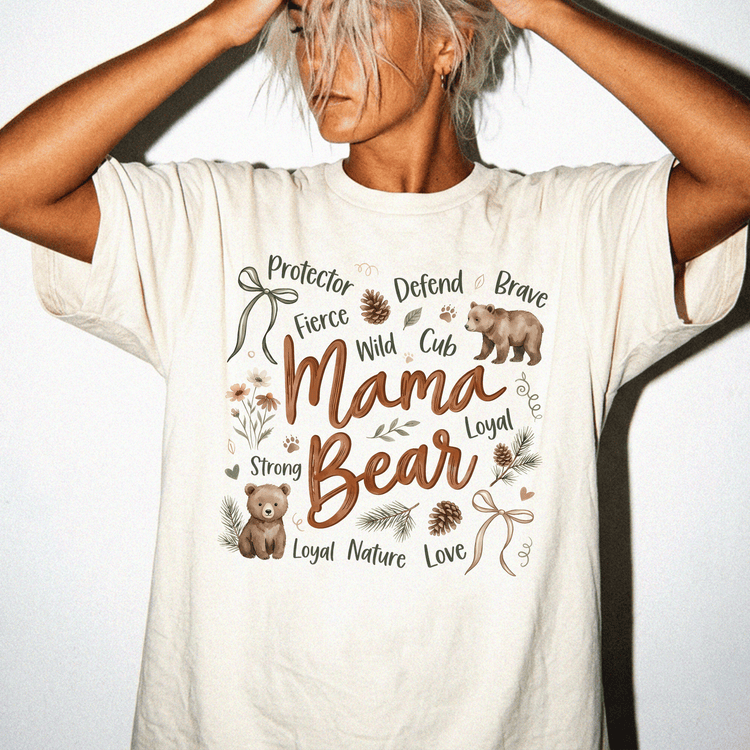 A woman wearing a white t-shirt with a graphic design featuring a bear and various words related to motherhood and nature.