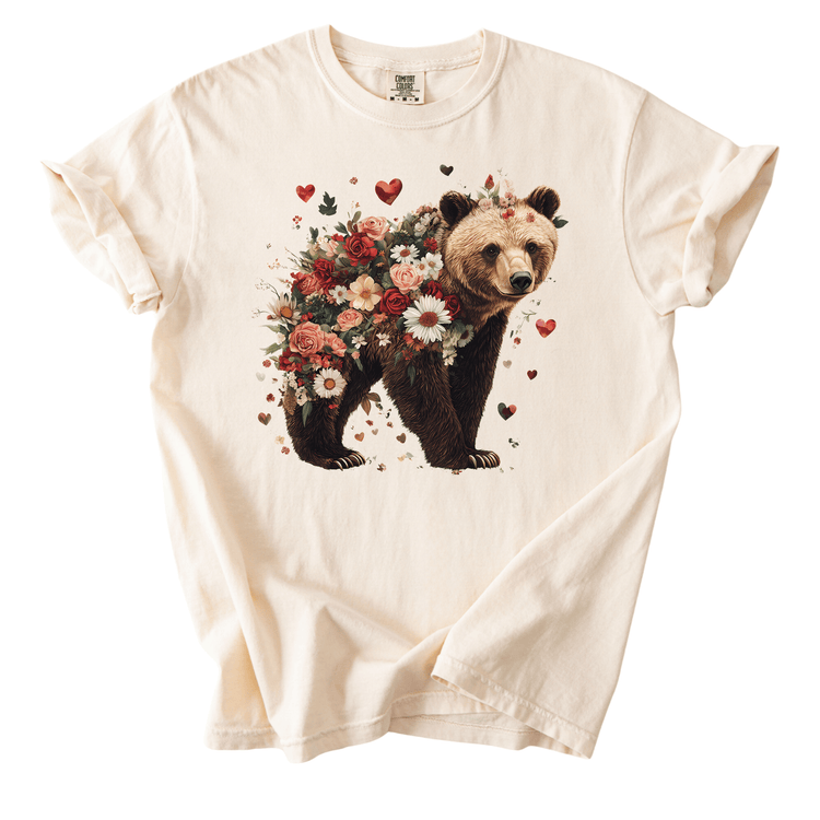 A white t-shirt with a printed image of a bear surrounded by a floral arrangement.