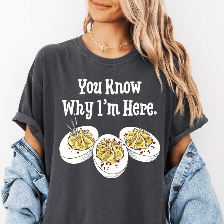 A woman wearing a gray t-shirt with a humorous text and three illustrations of deviled eggs.