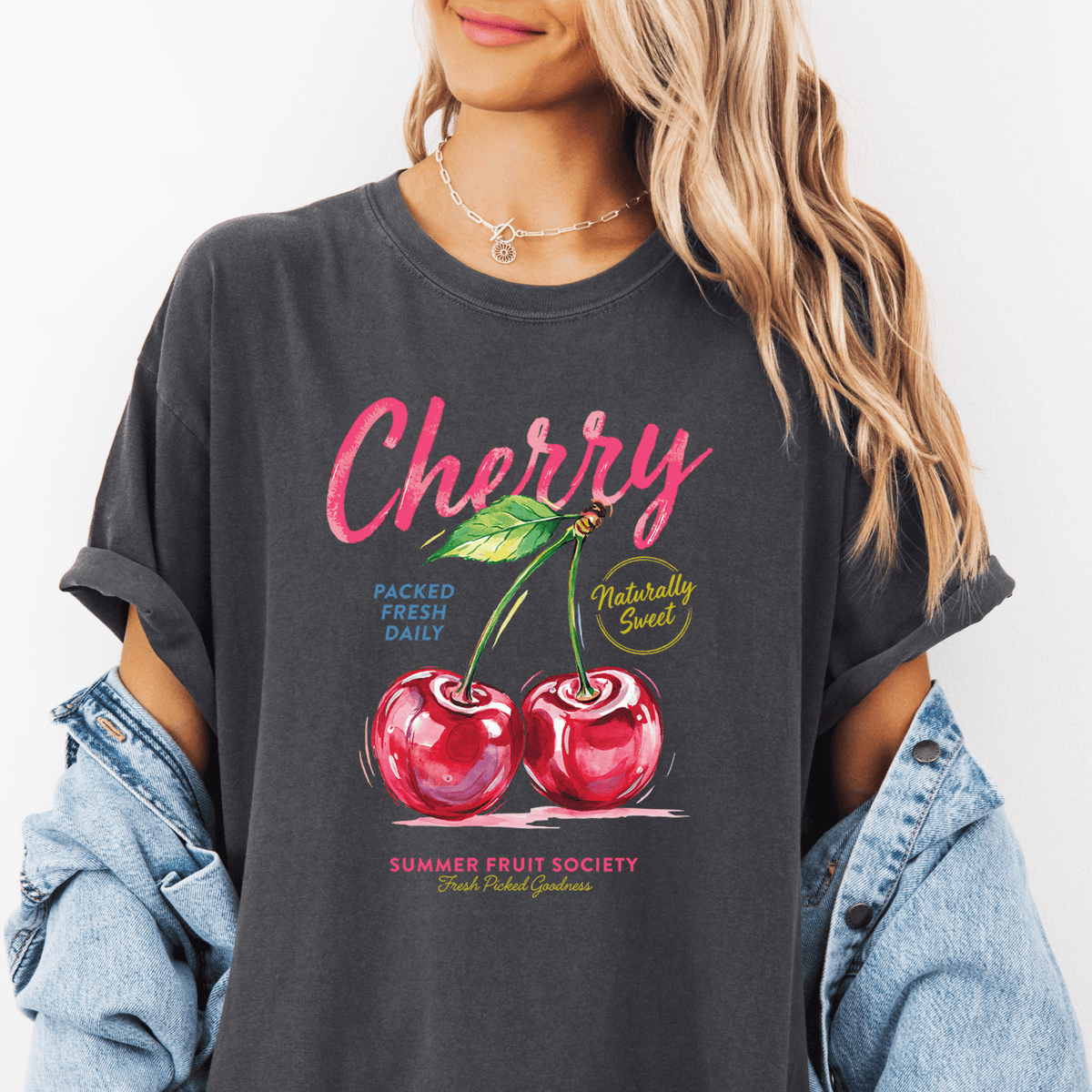 A woman wearing a gray t-shirt with a graphic design of cherries and text promoting a summer fruit society.