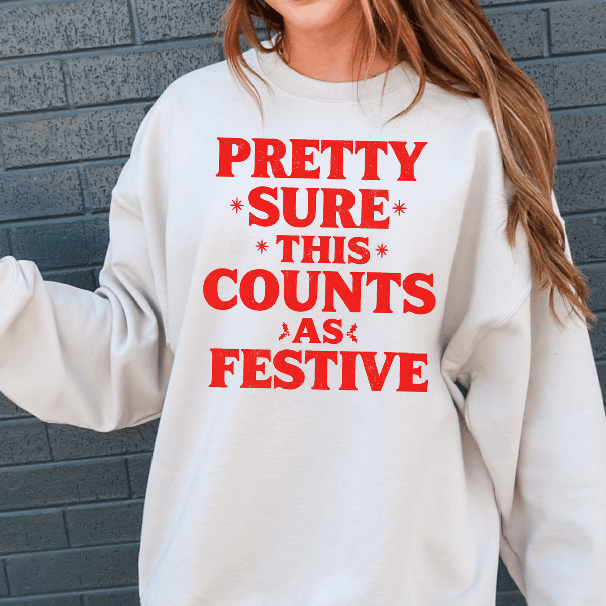 A white sweatshirt with red text that reads "PRETTY SURE THIS COUNTS AS FESTIVE" printed on it.