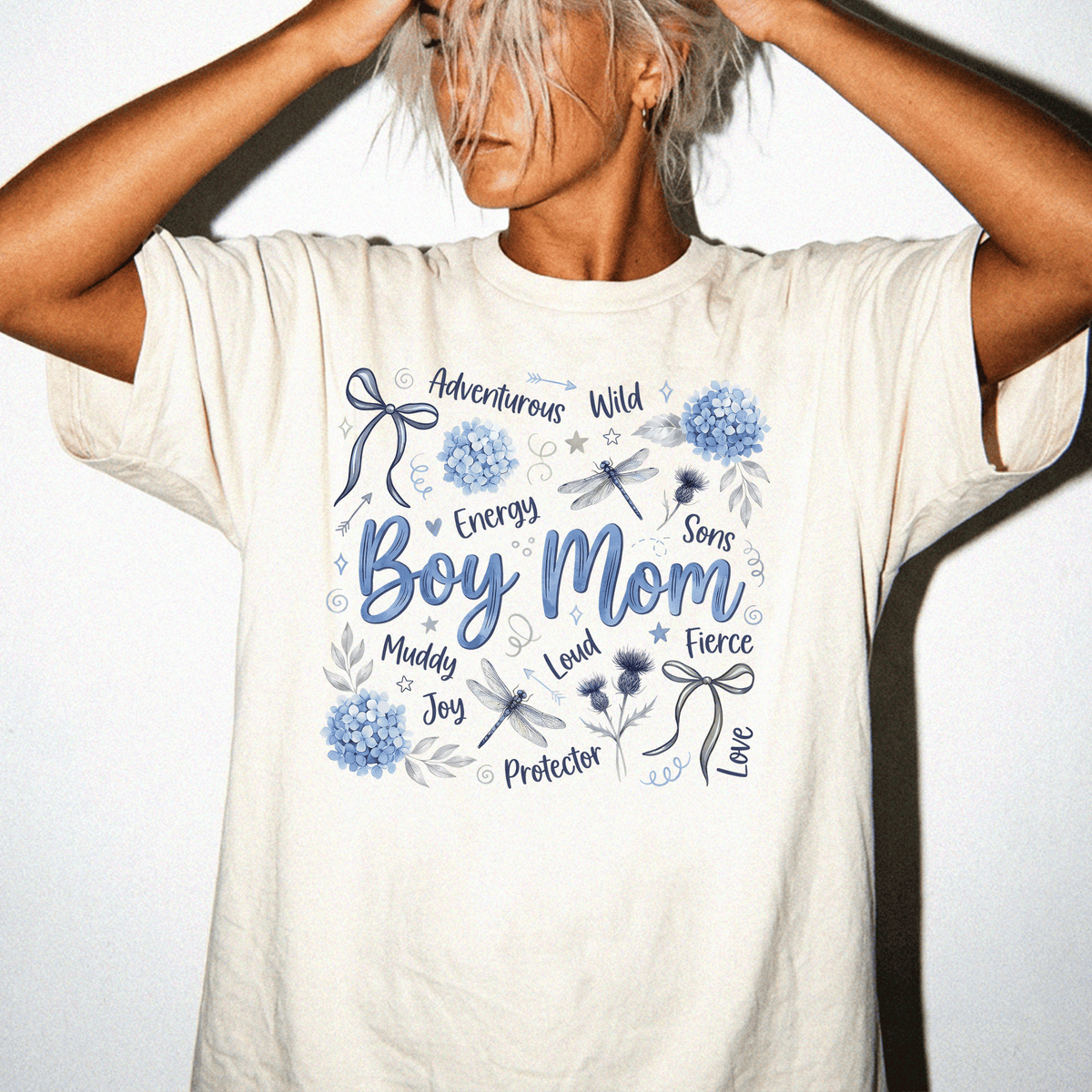A woman wearing a white t-shirt with a graphic design featuring various words and illustrations related to a boy's mother.