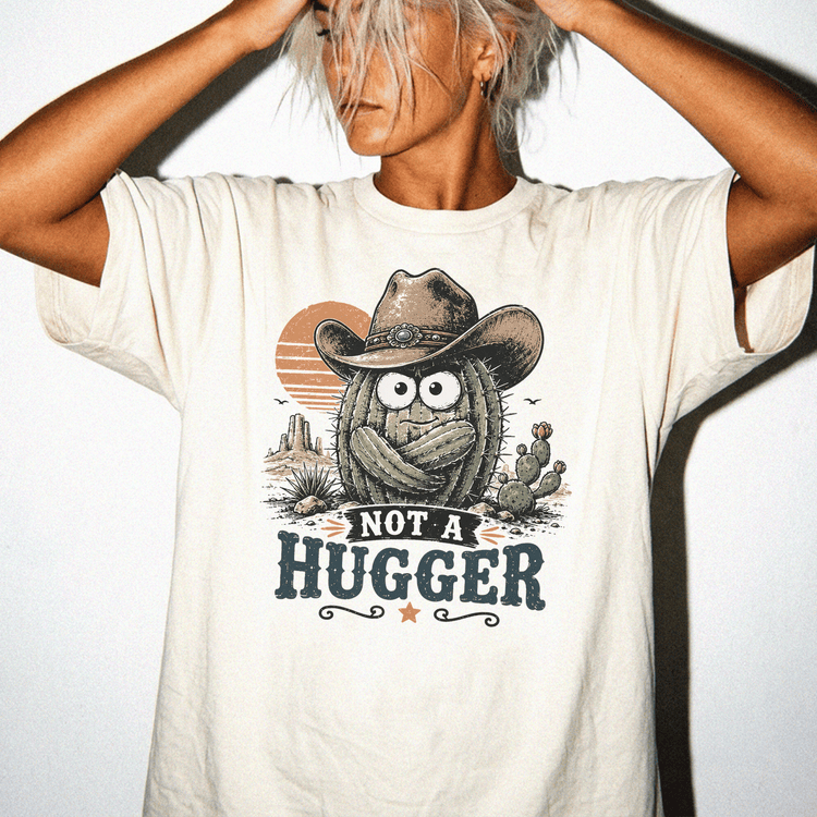 A person wearing a white t-shirt with a graphic design featuring a cactus character and the text "NOT A HUGGER".