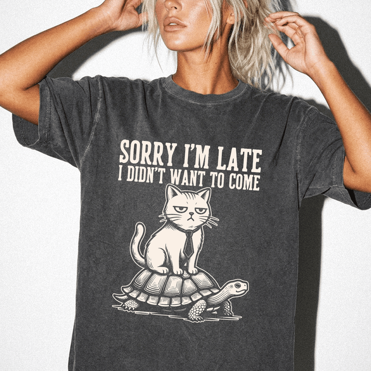 A woman wearing a gray t-shirt with a graphic design depicting a cat sitting on a turtle.