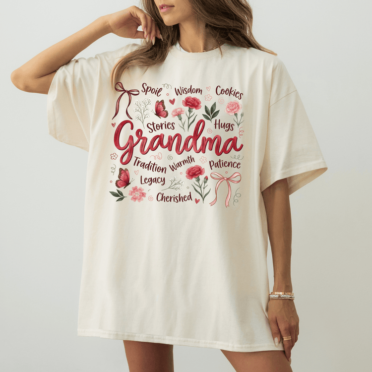 A woman wearing a white t-shirt with a graphic design featuring the words "Spoil, Wisdom, Cookies, Hugs, Grandma, Stories, Tradition, Legacy, Cherished" surrounded by various floral and ribbon elements.
