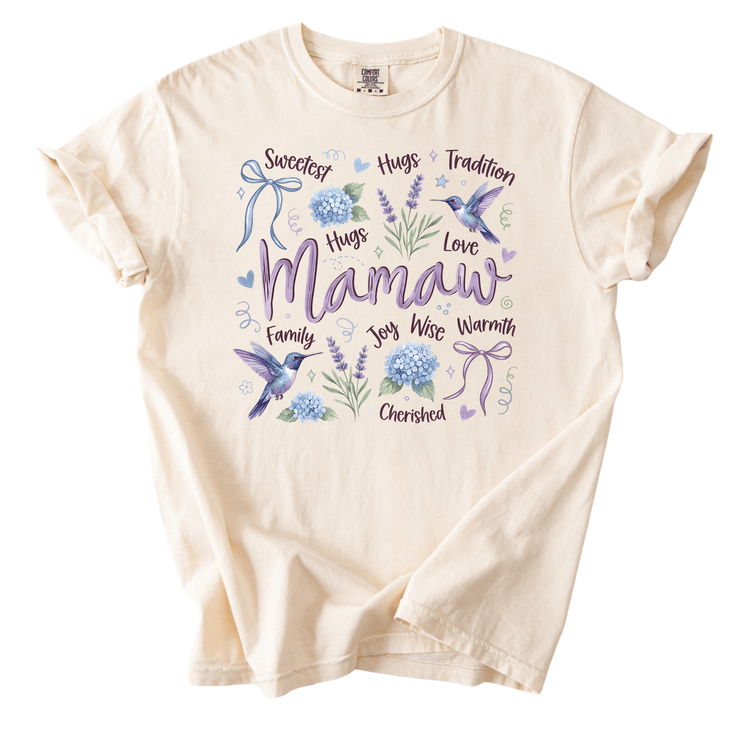 A white t-shirt with a graphic design featuring a bird, flowers, and the word "Mamaw" written in purple.