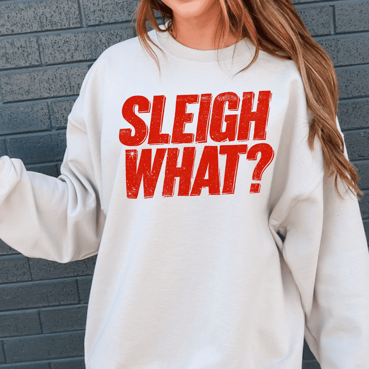 A person wearing a white sweatshirt with the text "SLEIGH WHAT?" printed on it.