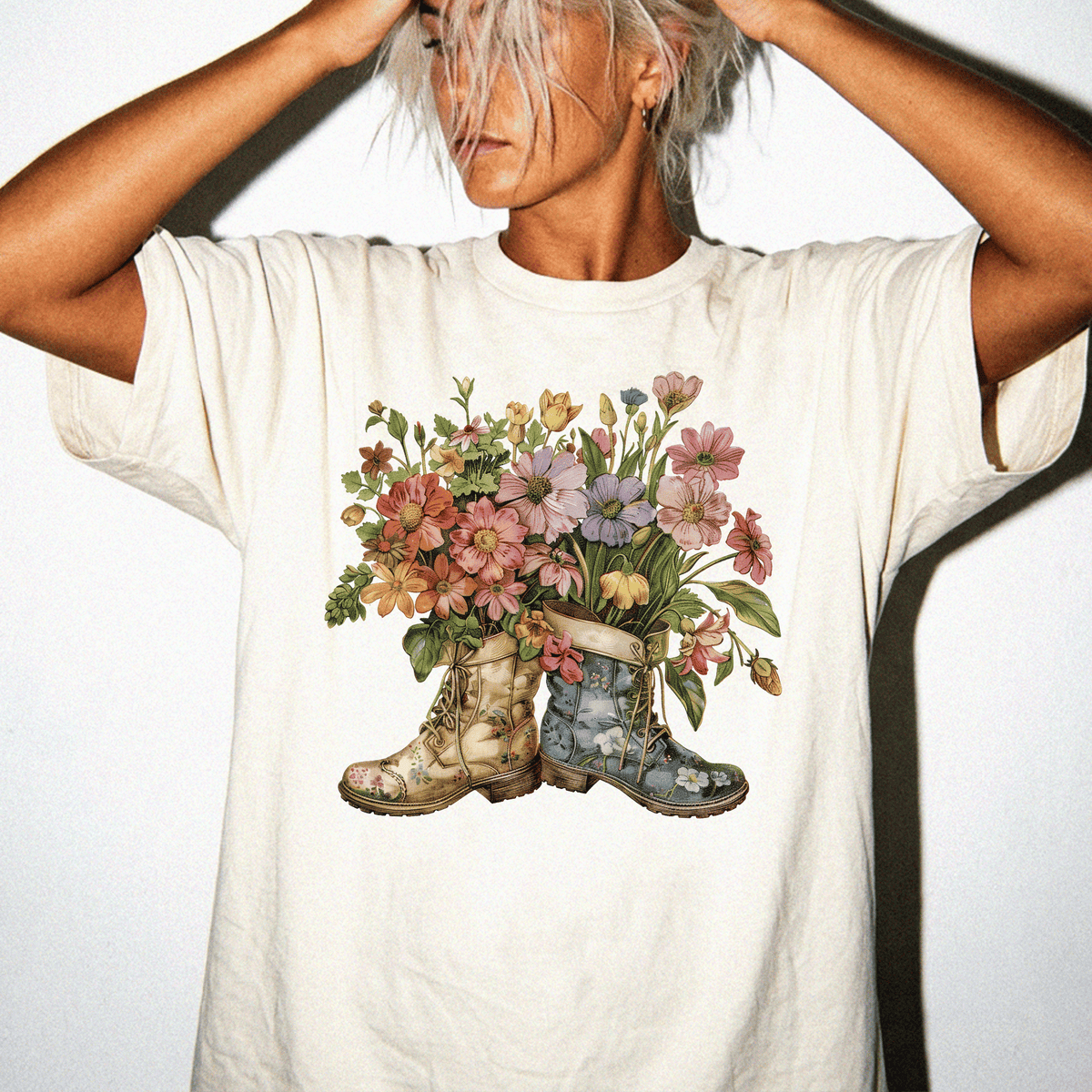 A woman wearing a white t-shirt with a colorful floral design of boots on the front.