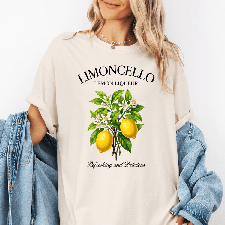 A woman wearing a white t-shirt with a graphic design of lemons and green leaves, along with the text "LIMONCELLO LEMON LIQUEUR" and "Refreshing and Delicious".