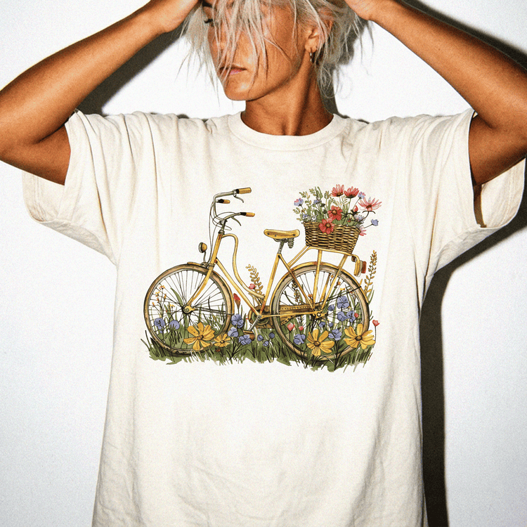 A woman wearing a white t-shirt with a bicycle and flowers printed on it.