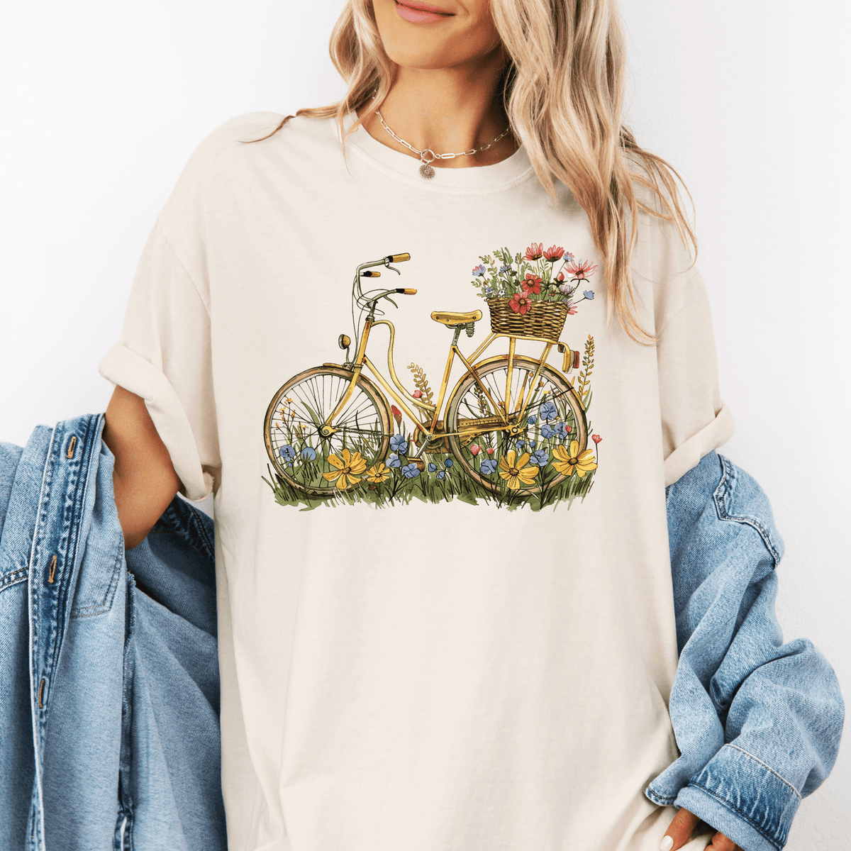 A woman wearing a white t-shirt with a graphic of a bicycle with flowers on the basket.